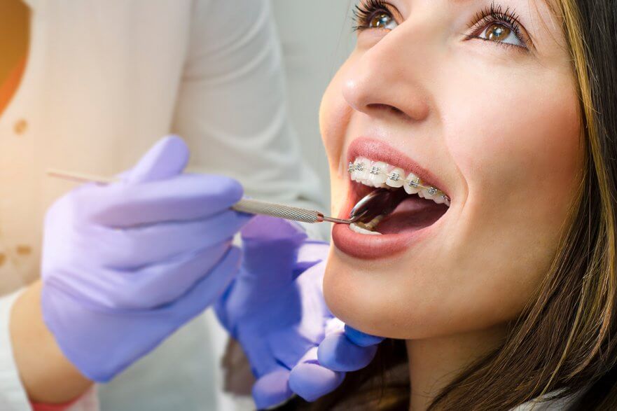Orthodontist examining braces of young woman in dental chair